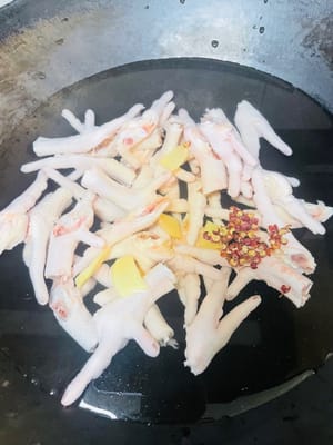 Coloque las patas de pollo limpias en una olla con agua fría. Añada rodajas de jengibre, granos de pimienta de Sichuan (o cebolletas) y vino de cocina. Hierva el agua, retire la espuma, reduzca el fuego a bajo, tape y cocine a fuego lento durante 10 minutos. Si prefiere una textura más suave, añada un minuto más al tiempo de cocción. Tenga cuidado de no sobrecalentar el fuego, ya que esto romperá la piel.