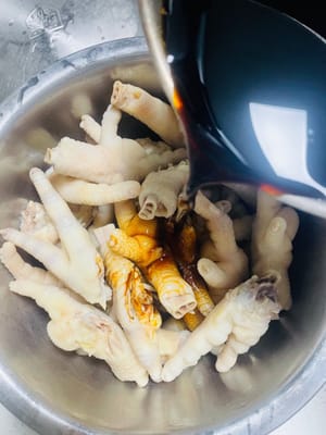 Coloque las patas de pollo frías en la salsa de vinagre previamente preparada y enfriada, asegurándose de que queden completamente sumergidas. Déjelas reposar toda la noche. Si prefiere el sabor a ajo y cebolla, añada una pizca de ajo y cebolla durante el remojo. Si su recipiente es grande, añada la salsa de vinagre en una proporción 1:1:1 de vinagre dulce, salsa de soja ligera y agua para asegurar que las patas de pollo queden completamente sumergidas.