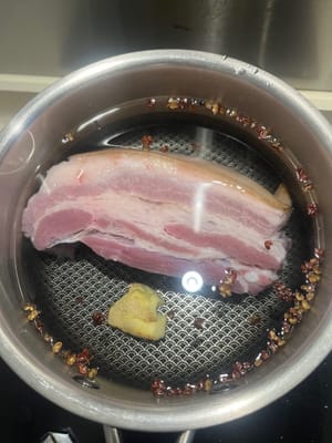 Ponga un poco de agua fría en la olla, agregue el jengibre, los granos de pimienta y la panceta de cerdo.