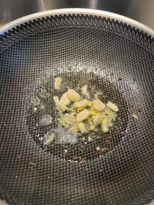 Calienta el wok y añade aceite. Sofríe el jengibre y el ajo hasta que suelten aroma. (Es importante usar un poco más de aceite en este paso; si hay poco, el cerdo quedará seco y no sabroso.)