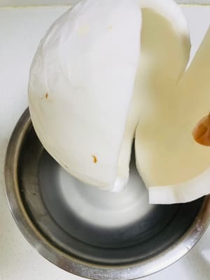 1.把老椰子褐色的表皮去除(讓賣椰子商家進行處理),清洗乾淨後放進一個稍大的容器裡,用刀將椰子切開,把椰子水倒出嚟裝好,最後使用,椰子殼備用。
2.注意椰子水不要和其他食材一起倒入鍋中,不然煮的時候容易揮發,太浪費了。