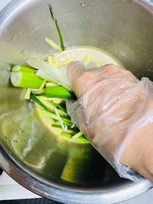 次に、ネギのセグメントとショウガのスライス（手で魚臭さを取り除くための材料）を洗って刻み、ボウルに入れ、冷ました熱湯50mlを加え、風味が出るまで力強くこすります（目的：ネギとショウガ自身の香りを利用して魚臭さを「こすり出す」ため、直接浸すよりも効果的です）。