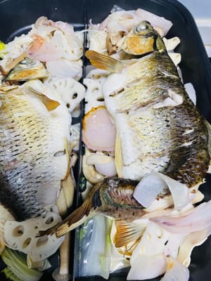 組み立てて、さあ、召し上がれ！大きめの天板を用意します。まず、下段に下ごしらえした付け合わせを敷き、その上に焼いた魚を乗せます。マイルドまたはスパイシーなソースをかけ、セロリ、コリアンダー、ピーナッツを散らします（カリカリがお好みなら、フライドピーナッツを加えてもOK）。

私は魚焼きグリル専用の天板を使いました。火をつけるとすぐに泡が立ち、食べながら焼くのが格別です。専用の天板がない場合は、小さなアルコールバーナーで普通の天板を挟んでも美味しくいただけます。