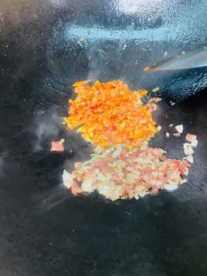 Aggiungere un altro cucchiaio d'olio, soffriggere la pancetta finché il grasso non si sarà sciolto, quindi aggiungere le cipolle tritate e soffriggere finché non saranno fragranti. Infine, aggiungere il kimchi e soffriggere a fuoco vivo per far sprigionare completamente il sapore aspro e piccante.