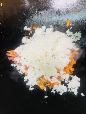 Versare il riso freddo e saltare velocemente fino a quando ogni chicco di riso non sarà ricoperto dal colore del kimchi e diventerà lucido e traslucido. Quindi aggiungere le uova strapazzate e saltare uniformemente con il riso.