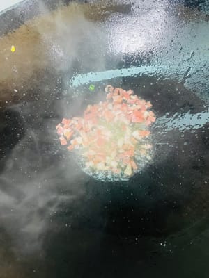 Aggiungere un altro cucchiaio d'olio, soffriggere la pancetta finché il grasso non si sarà sciolto, quindi aggiungere le cipolle tritate e soffriggere finché non saranno fragranti. Infine, aggiungere il kimchi e soffriggere a fuoco vivo per far sprigionare completamente il sapore aspro e piccante.