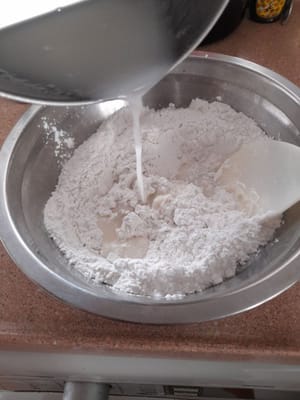 Versez le lait de coco petit à petit dans la farine de riz gluant. Remuez bien.