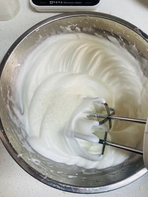 電動ミキサーを使って卵白を泡立て、砂糖40gを3回に分けて加えます（濃度は写真をご覧ください）。

1. 大きな泡が立つまで泡立て、砂糖の1/3を加えます。

2. 泡が細かくなったら、砂糖をさらに1/3加えます。

3. 卵白に柔らかいツノが立つようになったら、残りの砂糖の1/3を加えます。

ツノが立つまで泡立て続け、固いツノが立ったら止めます。泡立てすぎるとダマができてしまい、混ぜ合わせる際に潰れてしまいます。