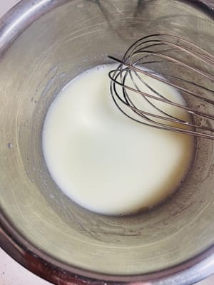 卵黄を入れたボウルにコーン油、牛乳、砂糖 20g を注ぎ、砂糖が溶けるまでかき混ぜます。