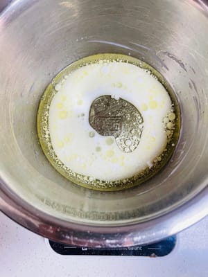 卵黄を入れたボウルにコーン油、牛乳、砂糖 20g を注ぎ、砂糖が溶けるまでかき混ぜます。