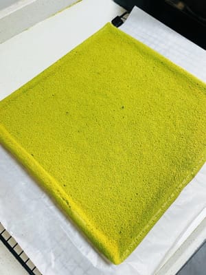 ケーキベースを冷まします。

焼き上がったら、ベーキングペーパーを網に敷きます。焼き上がったら網から取り出し、数回軽く叩いて余分な熱を逃がし、すぐに網にひっくり返します。天板を慎重に取り出します（熱いので注意してください）。次に、ベーキングペーパーをはがし、清潔なベーキングペーパーまたはベーキングマットをもう一枚重ねて覆います（水分の蒸発を防ぐためです。そうしないと、伸ばすときに割れてしまいます）。触っても熱くなくなるまで冷まします。冷めすぎないようにしてください。冷めすぎたケーキは脆くなり、伸ばすと割れてしまいます。

タオルのように簡単にケーキを巻けます！😀