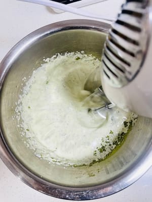 クリームフィリングを作る
夏場はエアコンをつけてクリームを泡立てるのを忘れないようにしてください。室温が高すぎるとクリームが溶けやすく、うまく泡立てられません（室温は20℃を超えないようにしてください）。生クリームに抹茶パウダー6gと砂糖20gを加え、手で数回かき混ぜてよく混ぜ合わせ、電動ミキサーで泡立てます。クリームが7割程度泡立つまで泡立て、その後低速に切り替え（泡立てすぎを防ぐため）、クリームがまっすぐ立つ程度（9割程度）になったら泡立てを止めます。泡立てすぎに注意してください（泡立てすぎるとバター状になり、使えなくなります）。