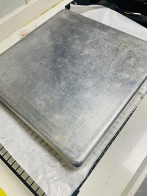 ケーキベースを冷まします。

焼き上がったら、ベーキングペーパーを網に敷きます。焼き上がったら網から取り出し、数回軽く叩いて余分な熱を逃がし、すぐに網にひっくり返します。天板を慎重に取り出します（熱いので注意してください）。次に、ベーキングペーパーをはがし、清潔なベーキングペーパーまたはベーキングマットをもう一枚重ねて覆います（水分の蒸発を防ぐためです。そうしないと、伸ばすときに割れてしまいます）。触っても熱くなくなるまで冷まします。冷めすぎないようにしてください。冷めすぎたケーキは脆くなり、伸ばすと割れてしまいます。

タオルのように簡単にケーキを巻けます！😀