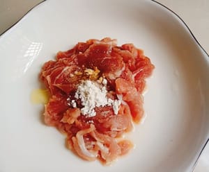 Ajoutez un peu de sel, un peu de poivre, un peu de vin de cuisine et une cuillère à café de fécule de patate douce à la viande tranchée, portez des gants et mélangez uniformément, puis ajoutez une cuillère à café d'huile de cuisson pour retenir l'humidité.