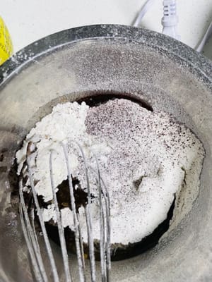 Ayak tepung terigu dan bubuk coklat ke dalam cairan kopi, aduk rata dengan gerakan membentuk huruf N.