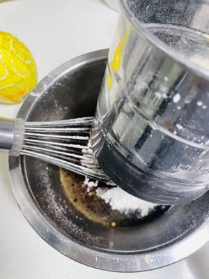 Ayak tepung terigu dan bubuk coklat ke dalam cairan kopi, aduk rata dengan gerakan membentuk huruf N.