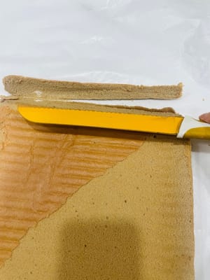 Dinginkan potongan kue, balikkan sisi depannya ke atas (untuk digulung nanti), lalu gunakan pisau untuk membuat beberapa potongan (tanpa memotong) agar mudah dibentuk saat digulung.
Permukaan kue saya jatuh, dan itu semua salah saya karena merobek kertas roti terlalu cepat dan kasar! Dan saat memanggang, saya melapisinya dengan kertas timah sebelum waktunya habis, yang juga memengaruhi kondisi permukaannya. Untungnya, kuenya digulung terbalik 😂