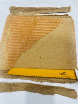 Dinginkan potongan kue, balikkan sisi depannya ke atas (untuk digulung nanti), lalu gunakan pisau untuk membuat beberapa potongan (tanpa memotong) agar mudah dibentuk saat digulung.
Permukaan kue saya jatuh, dan itu semua salah saya karena merobek kertas roti terlalu cepat dan kasar! Dan saat memanggang, saya melapisinya dengan kertas timah sebelum waktunya habis, yang juga memengaruhi kondisi permukaannya. Untungnya, kuenya digulung terbalik 😂