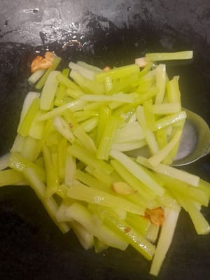 Prepare a frying pan, add 2 tablespoons of oil, saute the spices until fragrant, then add the celery stalks, stir well, then add the cooking wine, stir well, add all the spices, stir well.