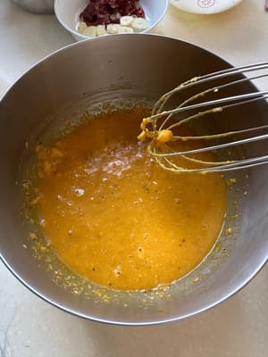 Comienza preparando la salsa para pasta. En un tazón grande, mezcla los huevos, la pimienta negra, el queso rallado y la mantequilla de pistacho hasta que estén bien integrados.