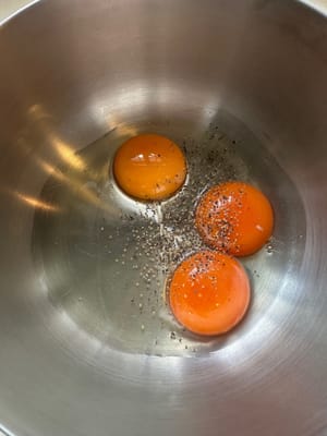 Comienza preparando la salsa para pasta. En un tazón grande, mezcla los huevos, la pimienta negra, el queso rallado y la mantequilla de pistacho hasta que estén bien integrados.