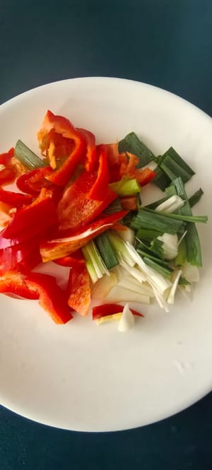 Die Chilischoten in Streifen schneiden, die Frühlingszwiebeln hacken und Ingwer und Knoblauch fein hacken.