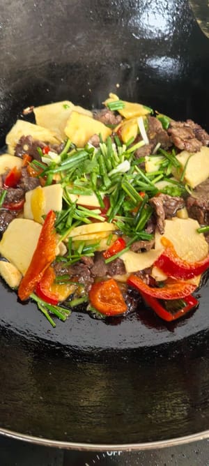 Das Rindfleisch dazugeben und kurz bei starker Hitze anbraten, dann mit gehackten Frühlingszwiebeln bestreuen.