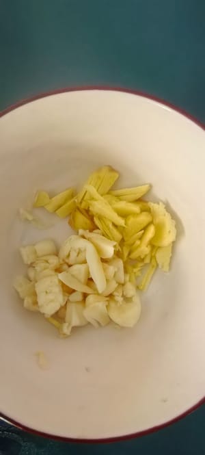 Die Chilischoten in Streifen schneiden, die Frühlingszwiebeln hacken und Ingwer und Knoblauch fein hacken.