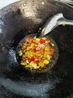 Leave some oil in the pan, add the prepared garlic and chili peppers. Stir fry quickly a few times.