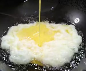 Heat the oil and pour in two eggs.