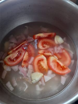 Das Wasser kocht, dann die sautierten Zwiebeln und den Knoblauch dazugeben, dann die Tomaten dazugeben, kochen, bis die Tomaten leicht welk sind.