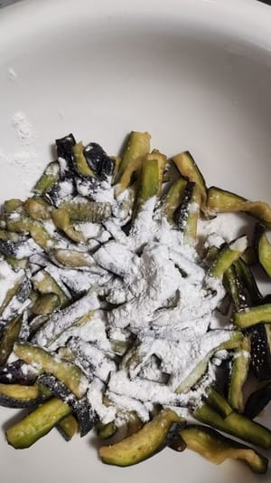 Tambahkan satu sendok teh garam dan rendam selama 10 menit. Kemudian, peras airnya dan tambahkan tepung kanji secukupnya, aduk rata hingga terong terbalut tepung kanji.
