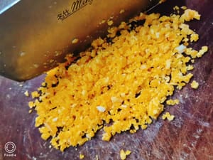 Cincang kuning telur kukus yang sudah diberi garam dengan pisau.