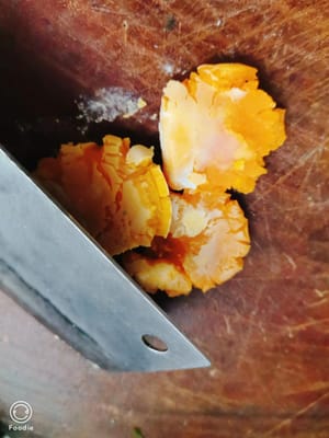 Cincang kuning telur kukus yang sudah diberi garam dengan pisau.