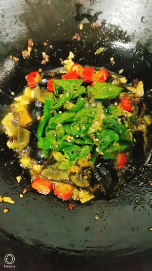 薄口醤油を小さじ1杯加えてマイルドな味に仕上げ、油を少し加えて7～8秒ほど炒めます。炒めた唐辛子を加え、さらに炒めます。チキンブイヨンを少々（お好みで）加え、強火で炒めます。