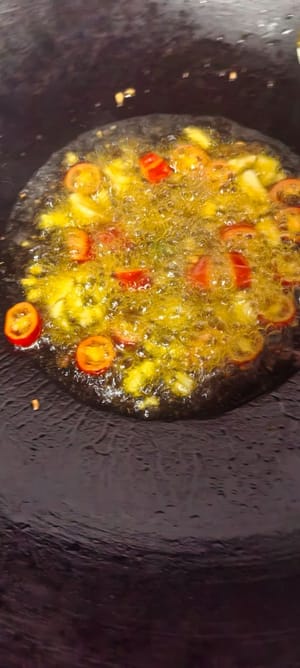 中華鍋に油を熱し、唐辛子、みじん切りにしたニンニク、発酵黒豆を加えて香りが出るまで炒めます。