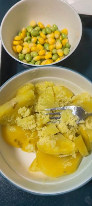 Schiacciare le patate al vapore con una forchetta, aggiungere i chicchi di mais e i piselli, un pizzico di sale e pepe e mescolare bene.