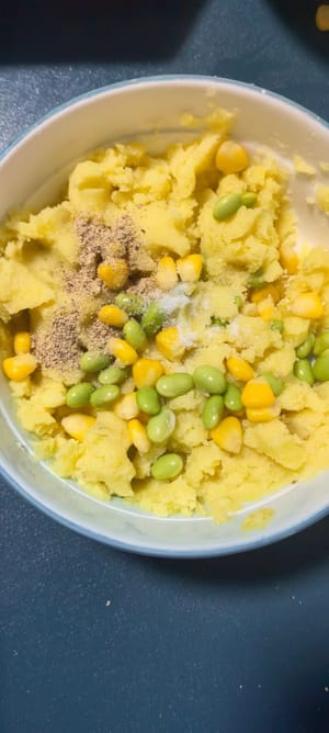 Schiacciare le patate al vapore con una forchetta, aggiungere i chicchi di mais e i piselli, un pizzico di sale e pepe e mescolare bene.