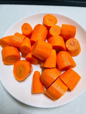 Préparer les carottes : Eplucher 500 g de carottes, les couper en dés, les laver et les égoutter.