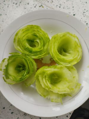 Utilisez les morceaux de fleurs pour faire quatre fleurs de concombre et placez-les sur une assiette.