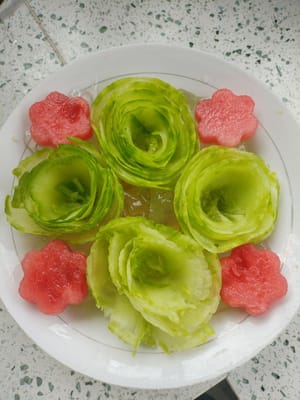 Placez quatre fleurs de pastèque dans l'espace entre les fleurs de concombre et la dentelle de concombre sur l'assiette.