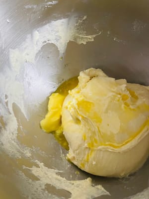生地をスピード2で3分間こね、材料をなじませます。その後、スピード5～6でさらに6分間こね、生地が少しギザギザの膜状になるまでこねます（完璧を目指さないでください。これはまだ半完成の膜です）。バターと塩を加え、スピード2で3分間こねてバターを吸収させます。その後、スピード5～6でさらに8～10分間こね、「グローブフィルム」（破ったときに滑らかな縁を持つ薄く半透明の膜。柔らかいパンを作る秘訣です！）になるまでこねます。