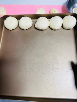 小さな生地のボールをもう少し膨らませる
小分けした生地のボールを丸めて天板に並べ、オーブンに入れます。湿度を保つため、近くに熱湯を入れたボウルを用意します。オーブンの温度を35℃程度に設定し、生地が2倍の大きさになるまで（柔らかくなり、小さな綿玉のような状態になるまで）発酵させます。