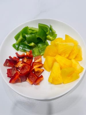 Tagliate a dadini i peperoni verdi e rossi e mettete da parte l'ananas.