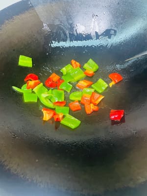 Scaldate l'olio in una padella, aggiungete i pezzetti di peperone verde e rosso e fateli rosolare per qualche minuto.