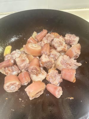 ใส่หางหมูลงไปแล้วผัดต่อจนหางหมูสุกเกรียมเล็กน้อย