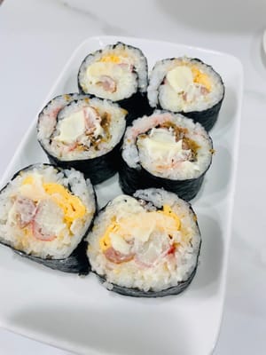 切分与装饰:
用锋利的刀将寿司卷切成小段,表面可再抹少许沙拉酱,方便粘合芝士片,再摆上甜虾。若有吞拿鱼、海草、鱼子等食材,也可随心添加。