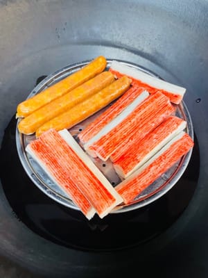 蒸制食材:把蟹柳棒和肠仔放入蒸锅,水开后蒸5分钟左右,取出。肠仔切开备用。