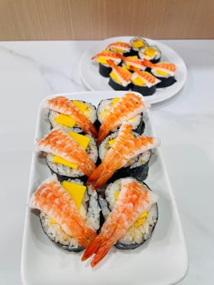 切分与装饰:
用锋利的刀将寿司卷切成小段,表面可再抹少许沙拉酱,方便粘合芝士片,再摆上甜虾。若有吞拿鱼、海草、鱼子等食材,也可随心添加。