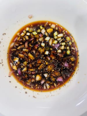 Préparez la sauce onctueuse (ingrédients non inclus dans la recette) : Dans un bol, mélangez l’ail haché, les échalotes émincées, 2 cuillères à soupe de sauce soja claire, 3 cuillères à soupe de vinaigre de riz, une demi-cuillère à soupe de sucre blanc, quelques graines de sésame blanc et un filet d’huile de sésame (2 gouttes). Remuez jusqu’à ce que le sucre soit dissous et laissez reposer 10 minutes pour que les saveurs se mélangent. Pour une version plus relevée, ajoutez un peu de piment en poudre.